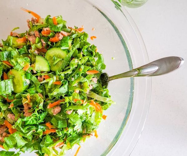 Glass of fresh water and healthy green food on a wooden table.