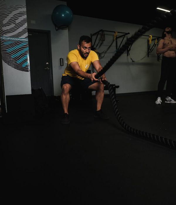 Man performing a core strength exercise in a modern, dark gym.